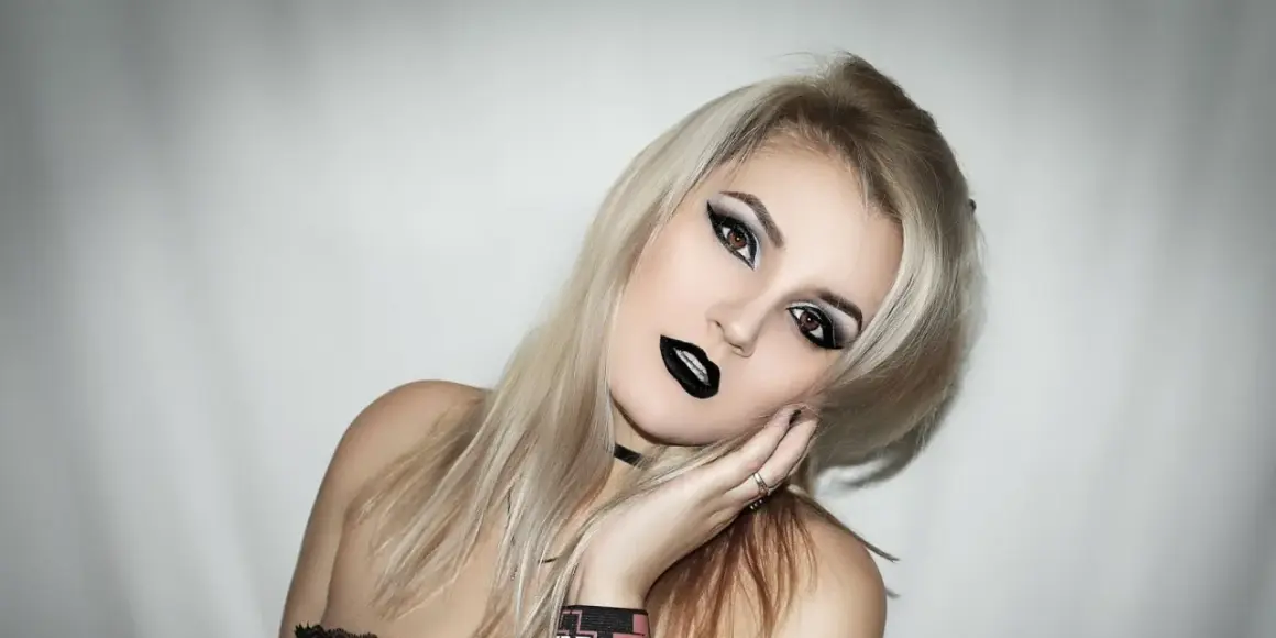 Une jeune femme avec une coiffure rock, maquillage intense et lèvres noires. Son regard est captivant.
