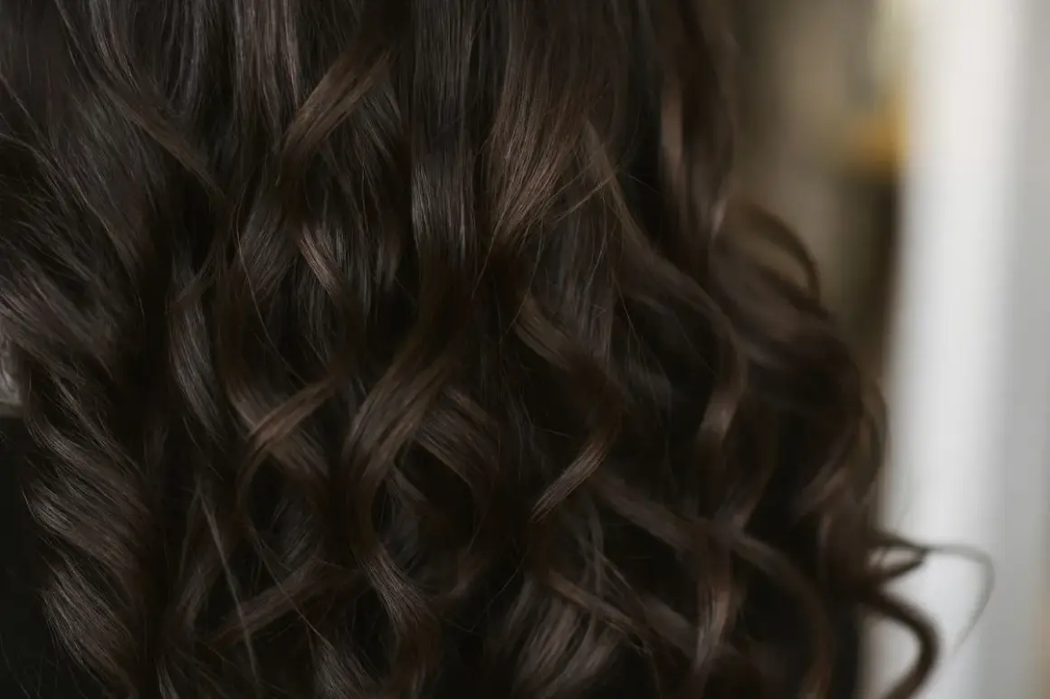 Chevelure brune aux reflets chauds, la couleur gloss cheveux révèle des ondulations soyeuses et lumineuses.