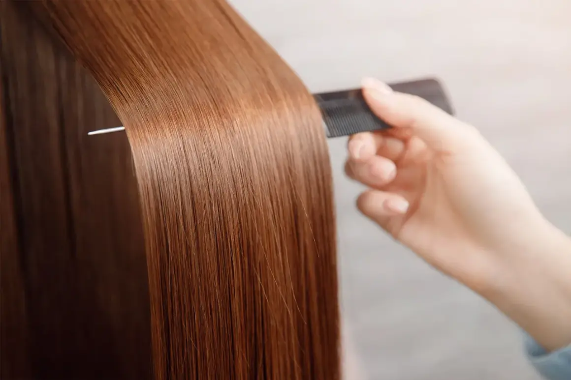 Une main peigne des cheveux longs et brillants, pour avoir les cheveux doux comme chez le coiffeur.