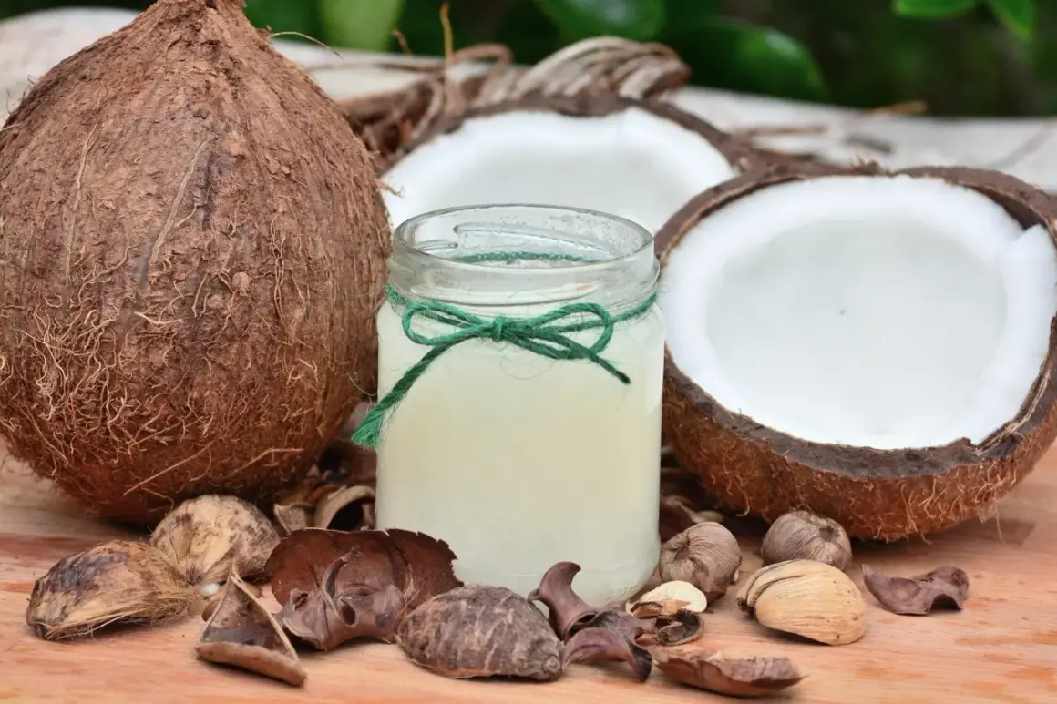 Un pot d'huile de coco, entouré de noix de coco coupées et de coques, un secret naturel pour des cheveux blancs éclatants.