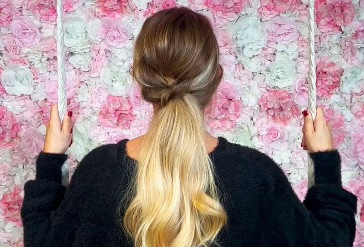 Coiffure semi attachée élégante avec une tresse torsadée, sur fond de mur de fleurs roses et blanches.