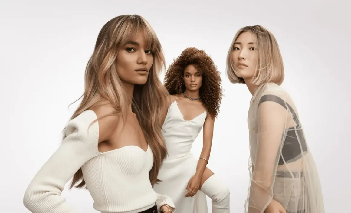 Trois femmes aux coiffures sublimes. La première arbore un french balayage blond, la deuxième des boucles rousses, la troisième un carré blond platine.