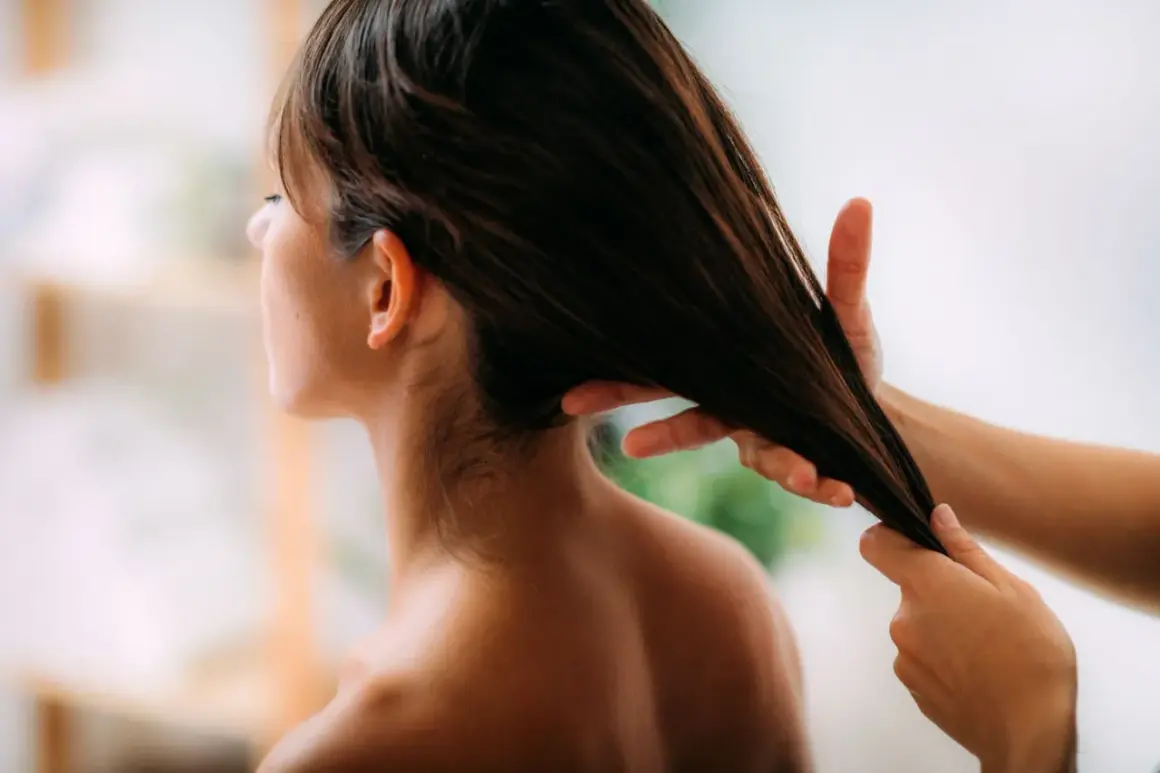 Application d'huile d'olive cheveux pour une brillance naturelle. Une main lisse une mèche de cheveux bruns.