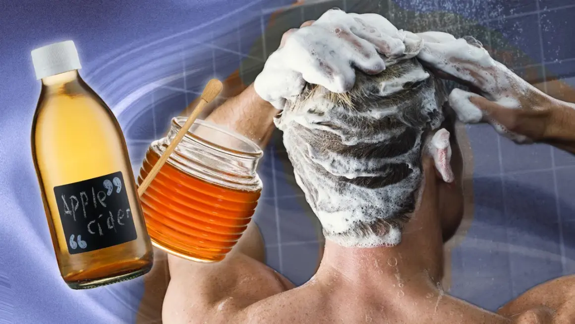 Une personne se lave les cheveux moussants, avec une bouteille de vinaigre de cidre et un pot de miel à proximité, pour éclaircir ses cheveux naturellement.