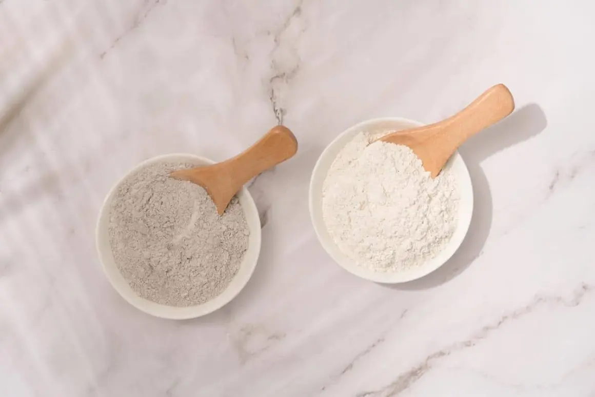 Deux bols de poudre, l'un gris et l'autre blanc, avec des cuillères en bois. L'argile blanche est parfaite pour les cheveux.