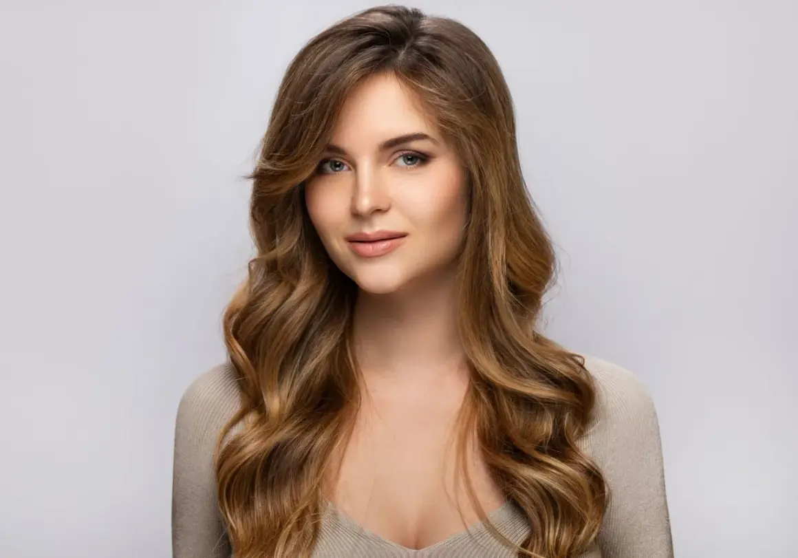 Une jeune femme au regard captivant, ses longs cheveux méchés ondulés encadrant son visage.