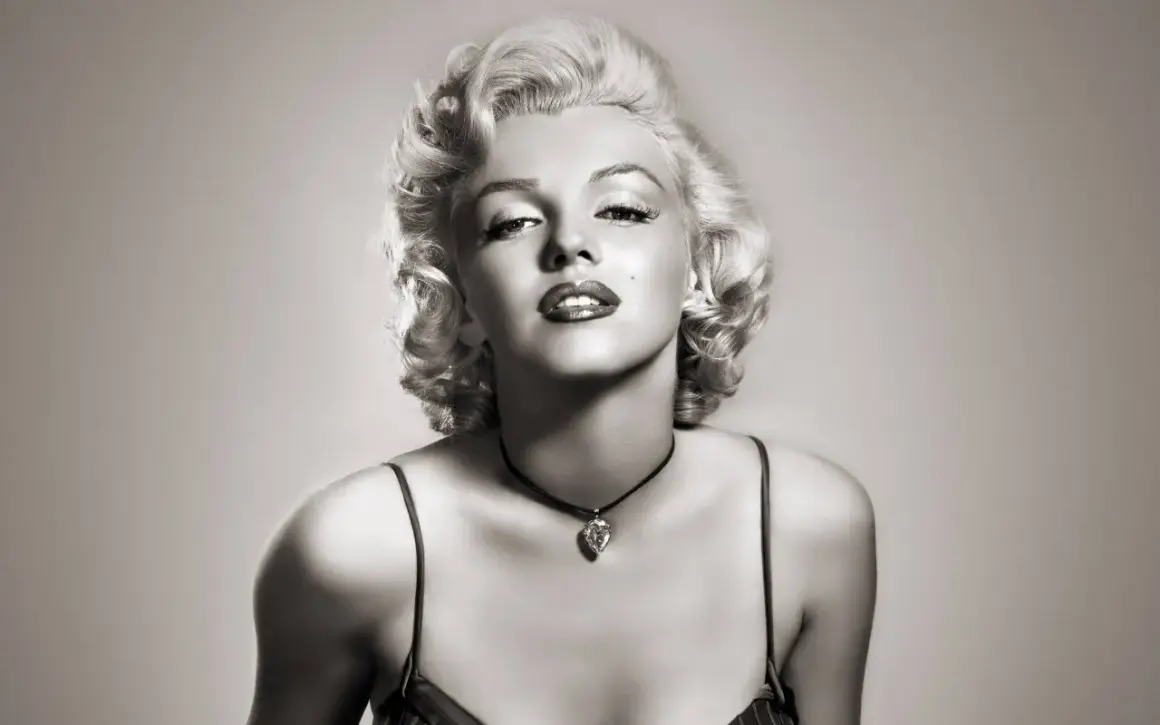 Icône glamour avec une coiffure année 50, maquillage marqué et un collier en forme de cœur.