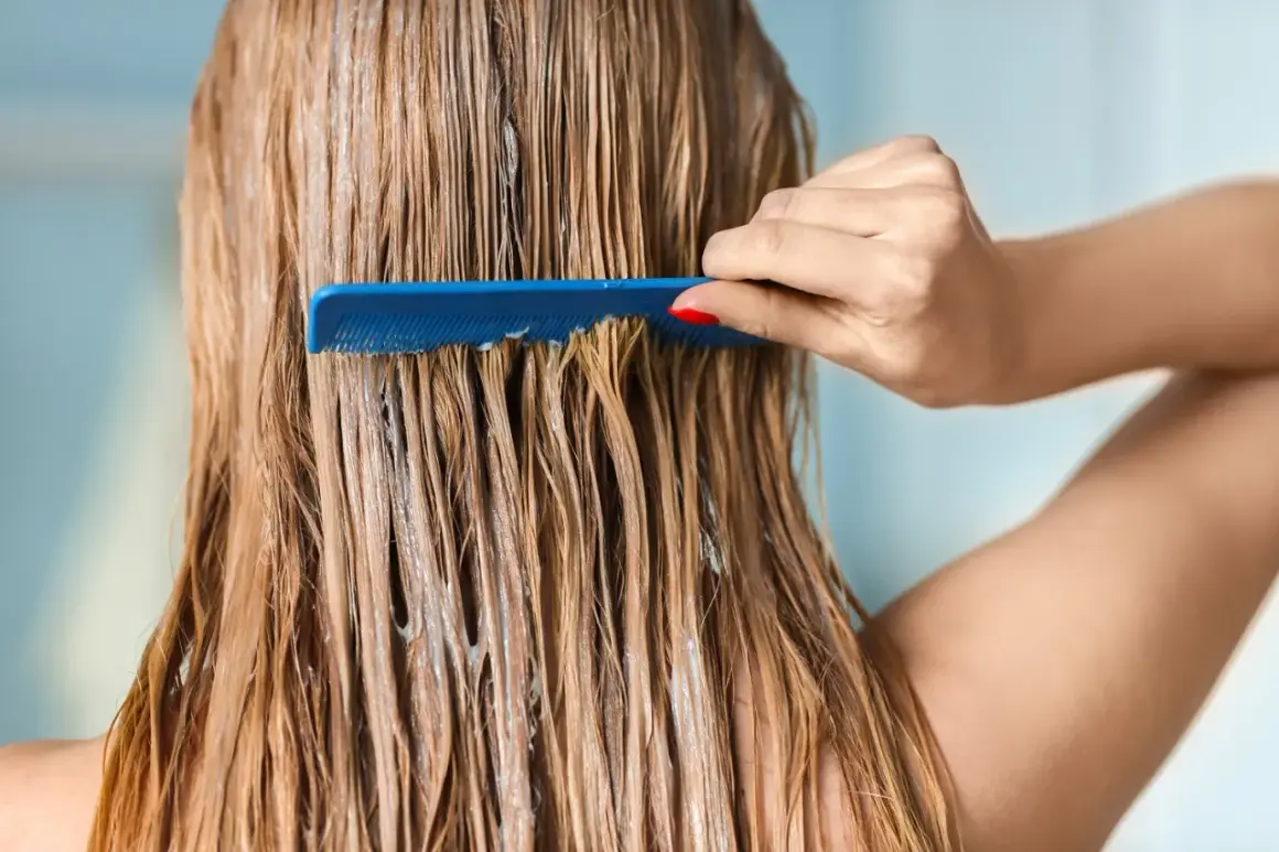 Une main peigne des cheveux blonds mouillés, recouverts d'un soin, peut-être pour changer de couleur de cheveux.