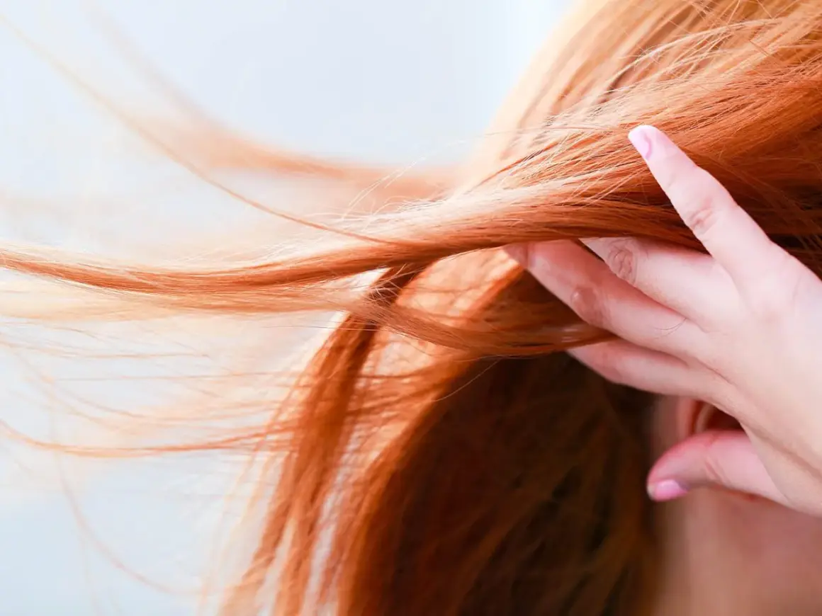 Chevelure rousse flamboyante, une main effleure les mèches. Quelle coloration pour enlever le roux ?