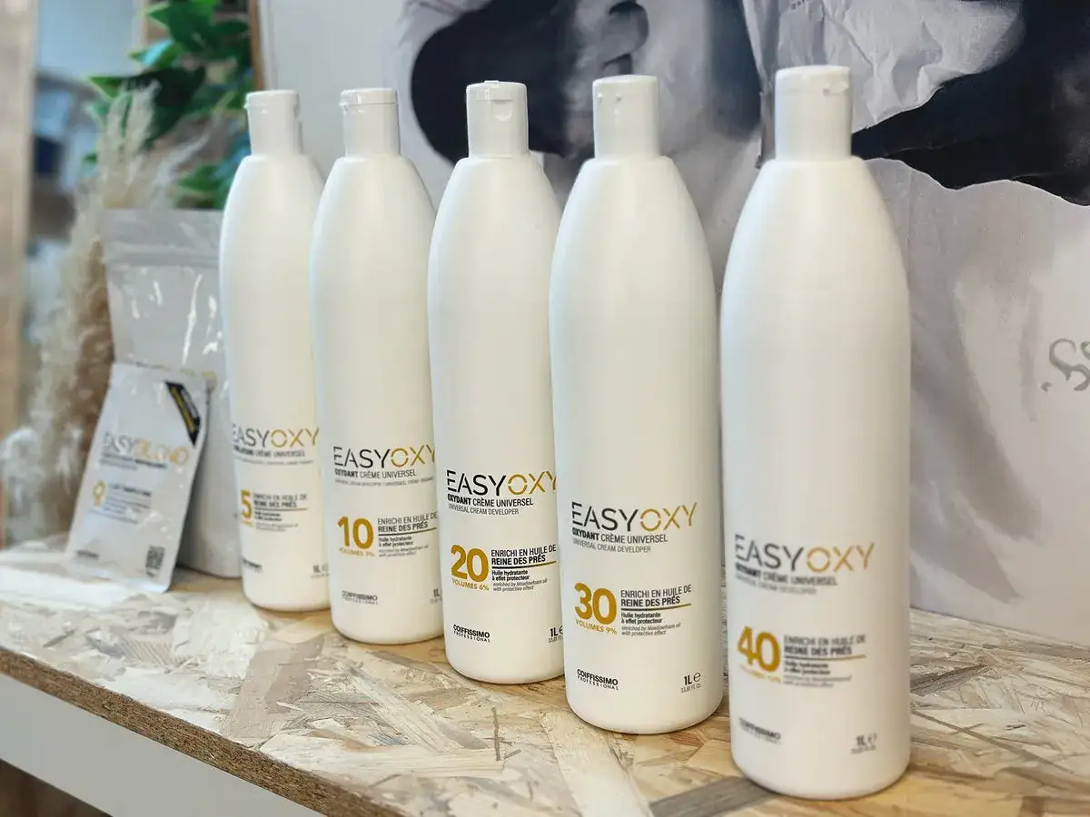 Cinq bouteilles d'oxydant EasyOxy, dont un 20 volumes et un 30 volumes, alignées sur une étagère.