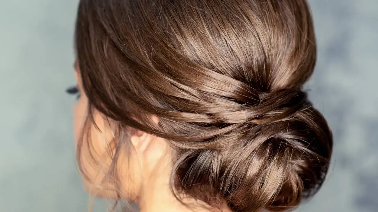 Un chignon bas flou, parfait pour un mariage, avec des mèches douces et naturelles.