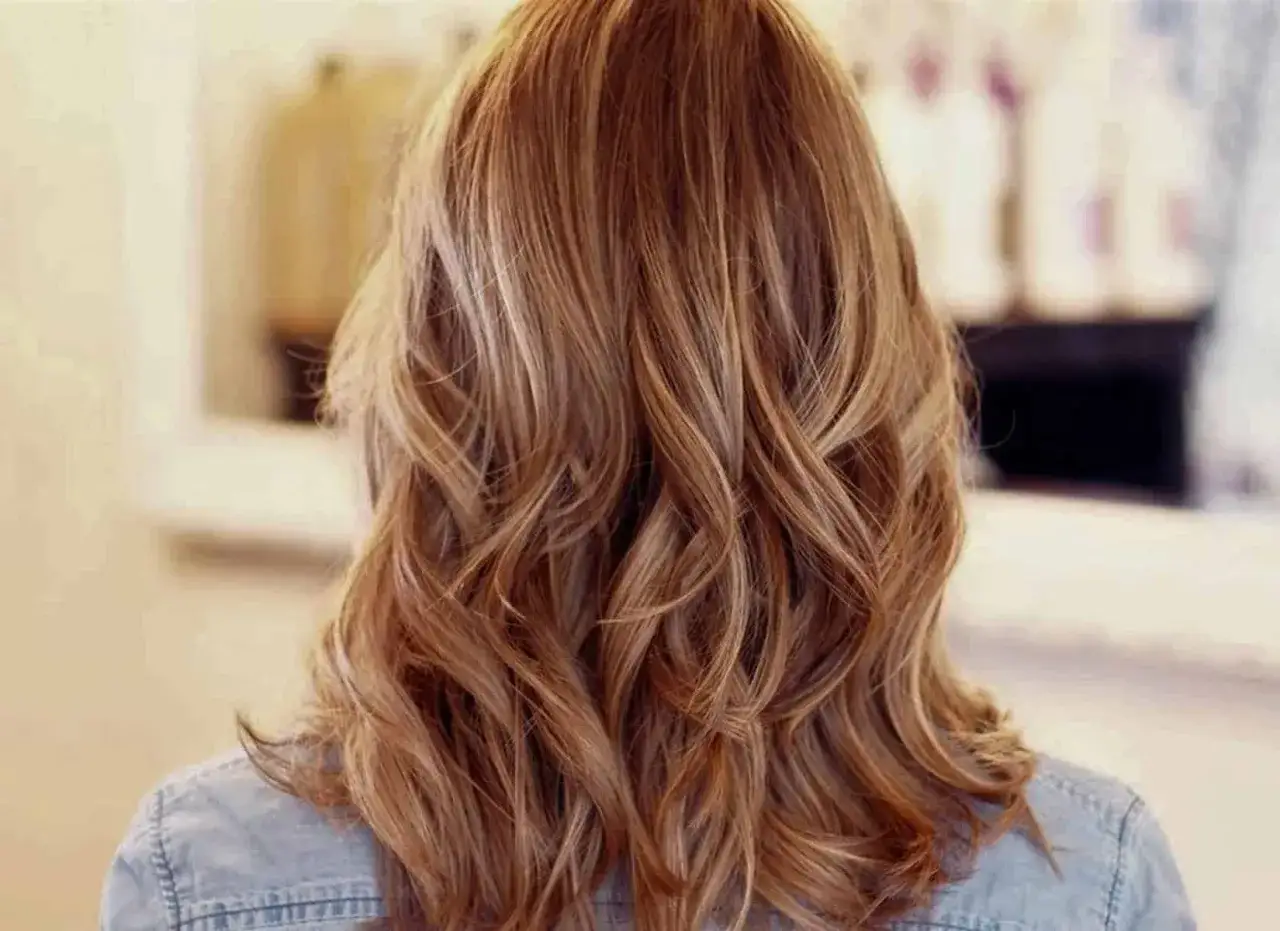 Chevelure ondulée avec des mèches foncées sur cheveux blonds, créant un effet naturel et lumineux.