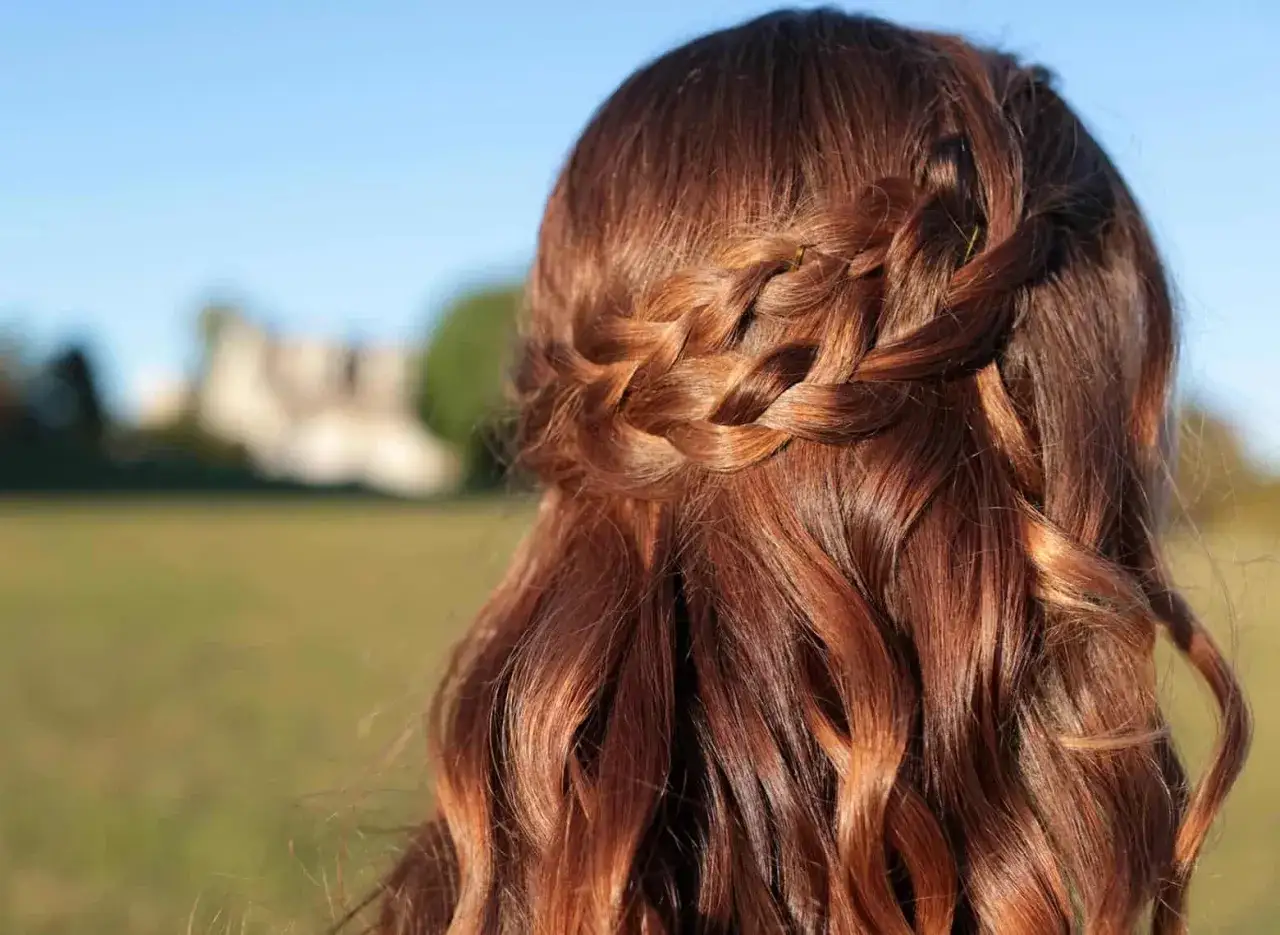 Chevelure châtain avec une tresse en couronne et des boucles.