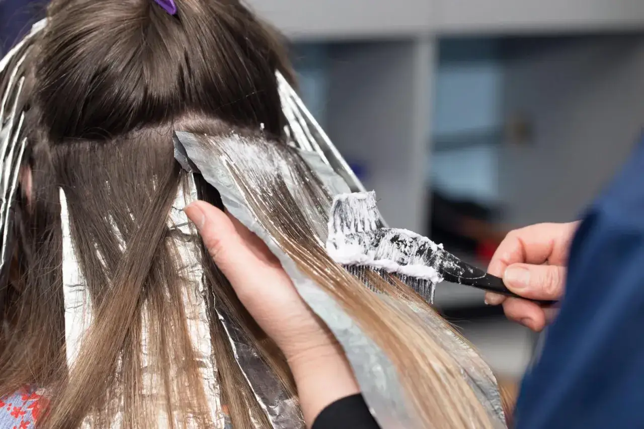 Coiffure en cours : application de produit d&eacute;colorant sur des m&egrave;ches. Pour savoir combien co&ucirc;te une permanente, il faut consulter un professionnel.