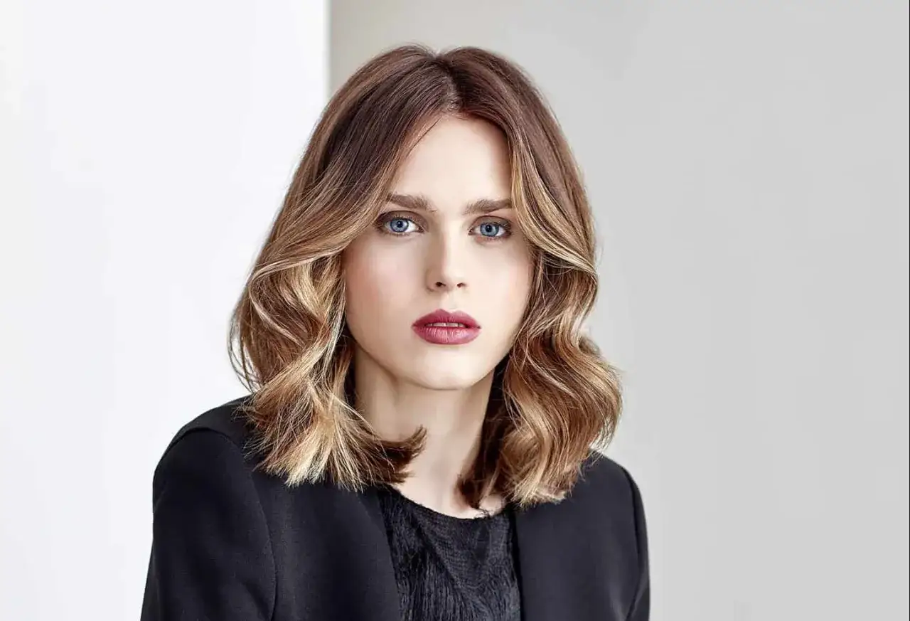 Une femme au regard intense, ses cheveux mi-longs aux reflets blonds et ch&acirc;tains, un ombr&eacute; hair contouring parfait.