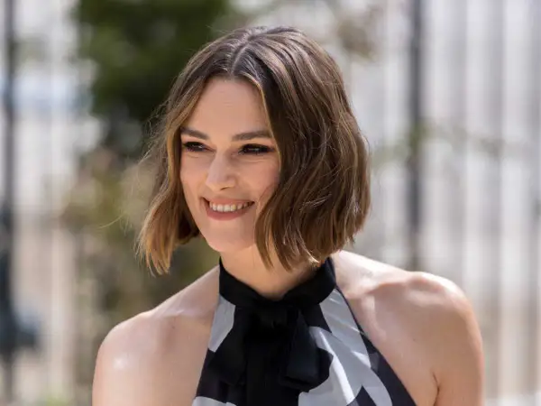 Une femme souriante, la cinquantaine, arbore une coupe dégradée qui donne du volume à ses cheveux fins et plats.