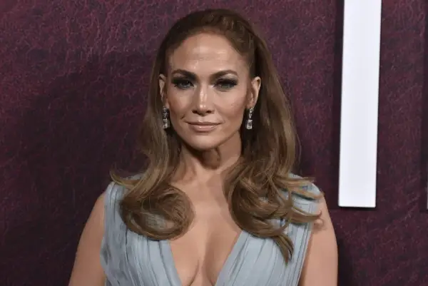 Jennifer Lopez, radieuse, arbore une élégante demi queue de cheval, des boucles tombant sur ses épaules. Elle porte une robe bleu pâle et des boucles d'oreilles scintillantes.