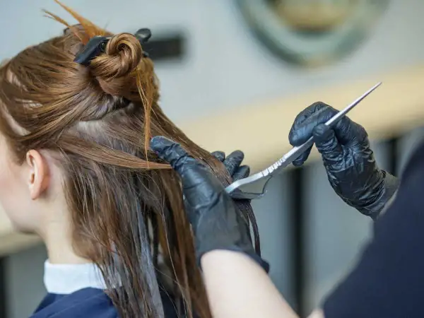 Application d'un soin capillaire sur des cheveux bruns avec une brosse.