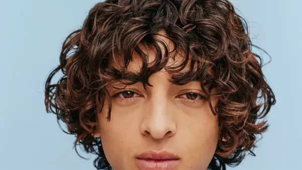 Gros plan sur un visage aux yeux marron et à la coiffure cheveux frisés bruns et volumineux.