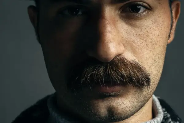 Gros plan sur le visage d'un homme, mettant en valeur un type de moustache broussailleuse et épaisse, aux reflets roux et bruns.