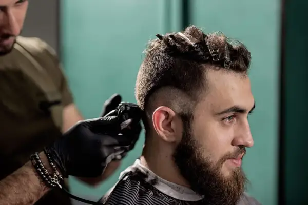Un homme se fait couper les cheveux en coupe mohawk court par un coiffeur.
