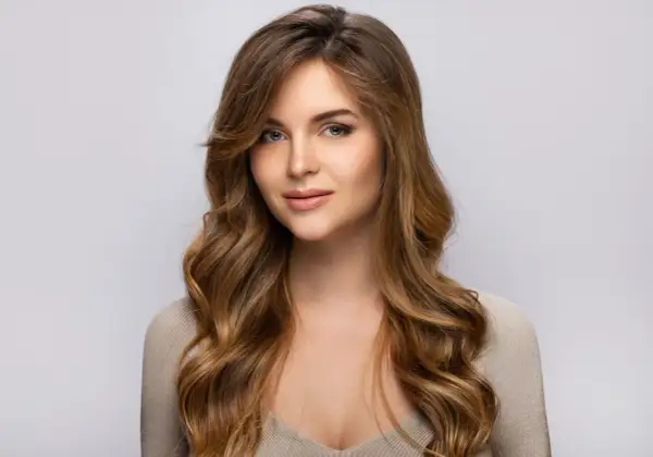 Une jeune femme au regard captivant, ses longs cheveux méchés ondulés encadrant son visage.