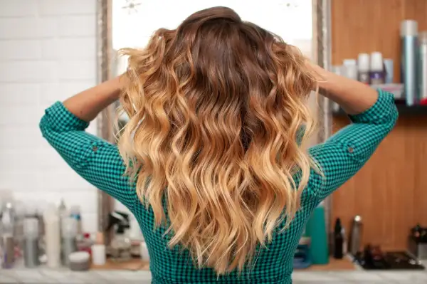Cheveux longs ondulés avec un dégradé blond obtenu par décoloration cheveux maison.