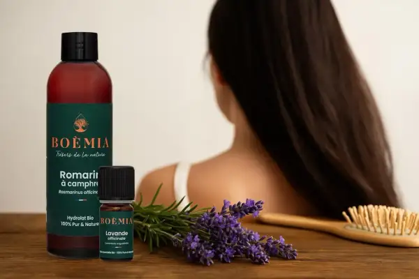 Flacon et petite fiole d'huile essentielle pousse cheveux, lavande et romarin, sur fond de cheveux longs.